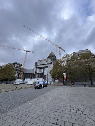 Cranes stand next to the Palace of Justice under a grey sky in Brussels.