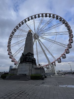 A Ferris wheel stands behind a stone monument on the Place Poelaert in Brussels.