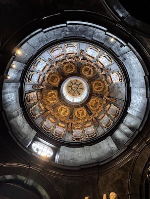 A round domed ceiling with gold decoration rises above a chapel in the Sablon church.