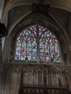 A large Gothic stained glass window lights the Sablon church in Brussels.