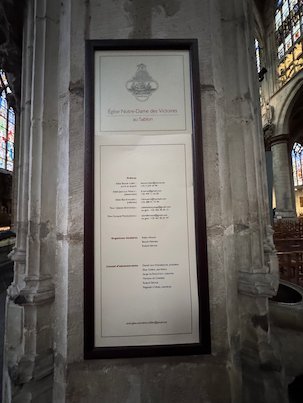 A framed information panel hangs on a pillar in the Sablon church in Brussels.