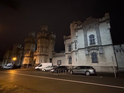 The towers of Saint-Gilles Prison stand next to a dark street at night in Brussels.