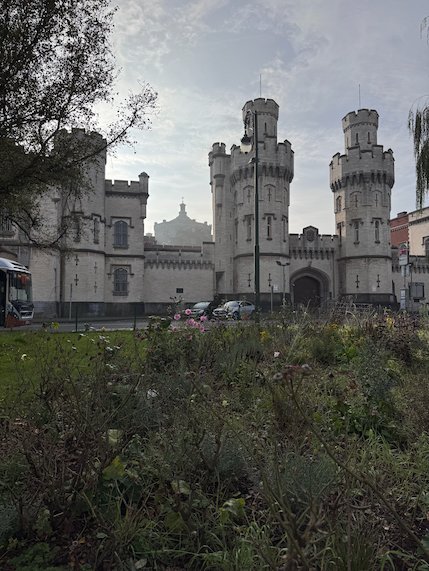 The castle-like towers of Saint-Gilles Prison rise behind a green field in Brussels.