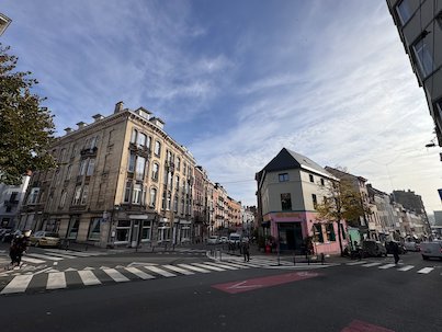 A pedestrian crossing leads to a corner with old houses in Saint-Gilles, Brussels.