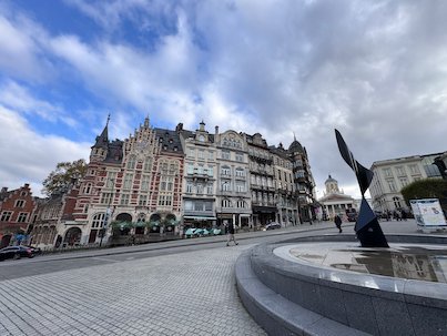 A dark sculpture stands in a round fountain on a square in Brussels.