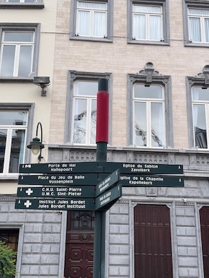 A signpost with directions to churches and squares stands on a street in Brussels.