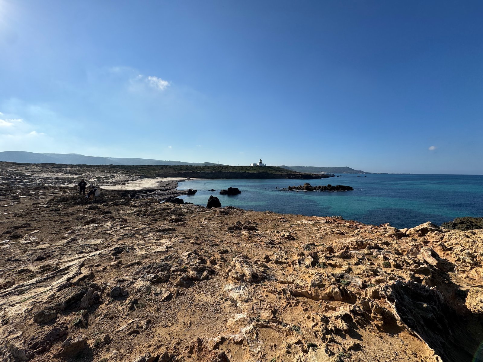 Layered limestone rocks lead down to turquoise sea on the coast at Cap Angela, Tunisia.