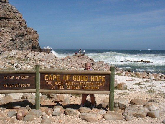 A wooden sign marks the Cape of Good Hope on a rocky beach in South Africa.
