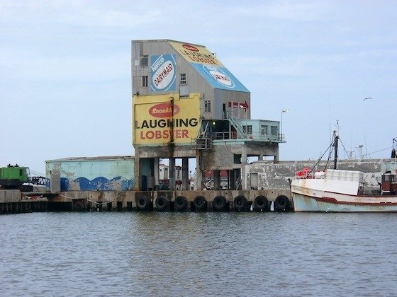 A fishing harbour building with a large Laughing Lobster sign near Cape Town in South Africa.