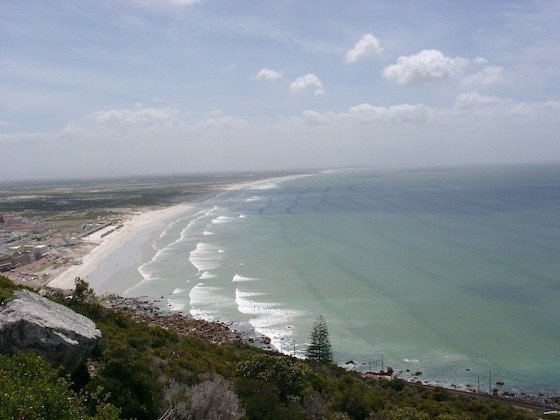 A long white sandy beach curves along the coast of the Cape Peninsula near Cape Town.