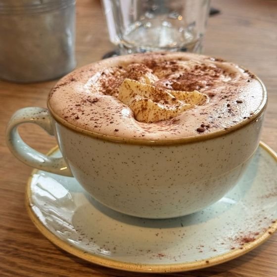 A cappuccino dusted with cinnamon is served at a café table during a Stockholm fika break, photographed by Zayera Khan