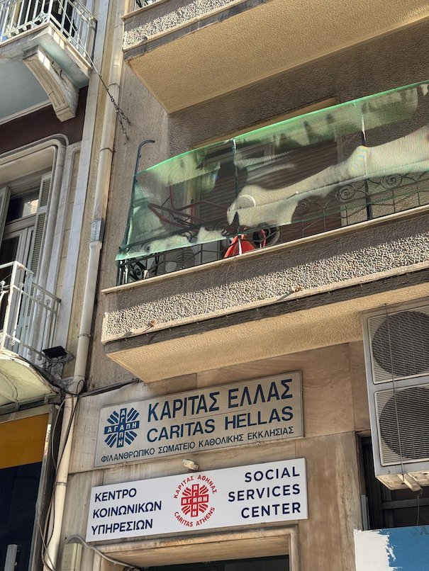 Entrance of the Caritas Hellas Social Services Center in Athens, with signs in Greek and English