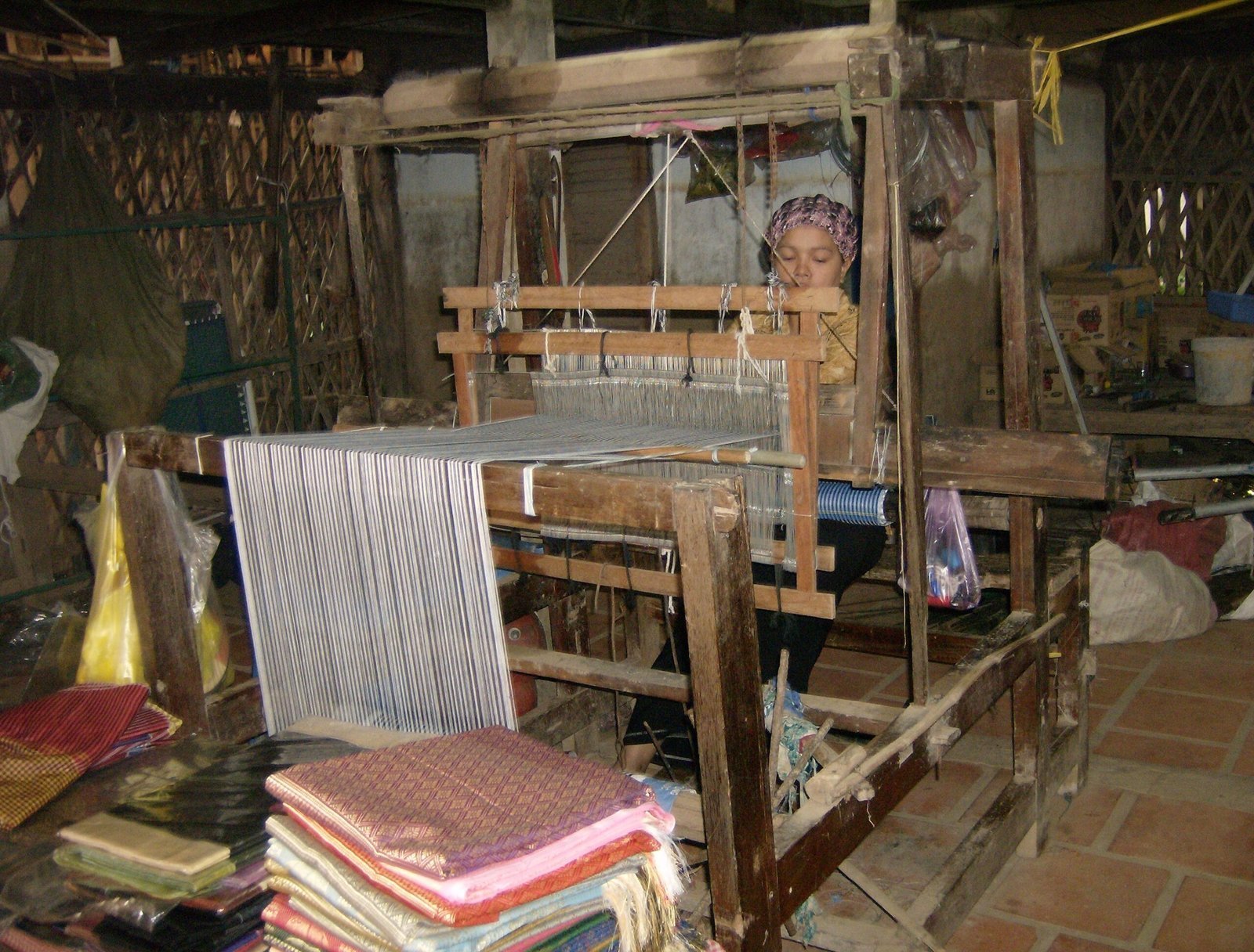 A woman sits at a wooden loom in a weaving workshop near Chau Doc.