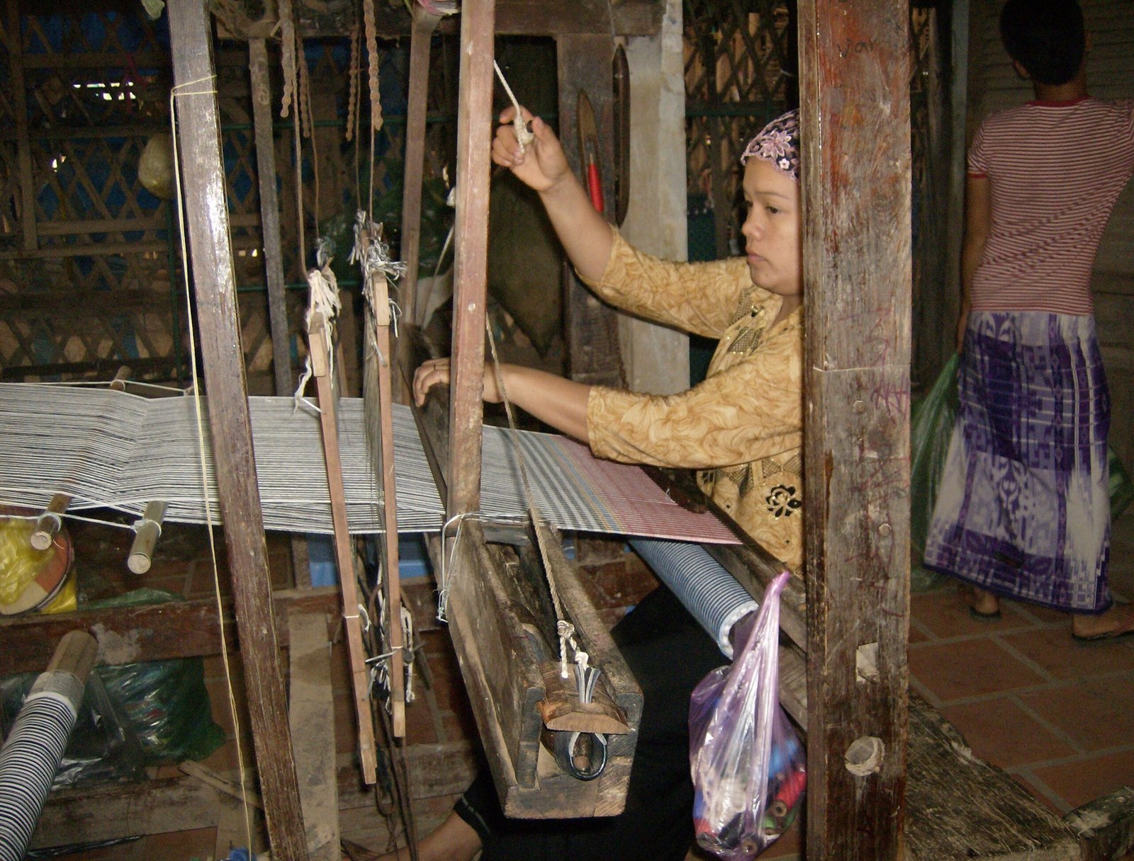 A woman weaves cloth on a traditional wooden loom in a village near Chau Doc.