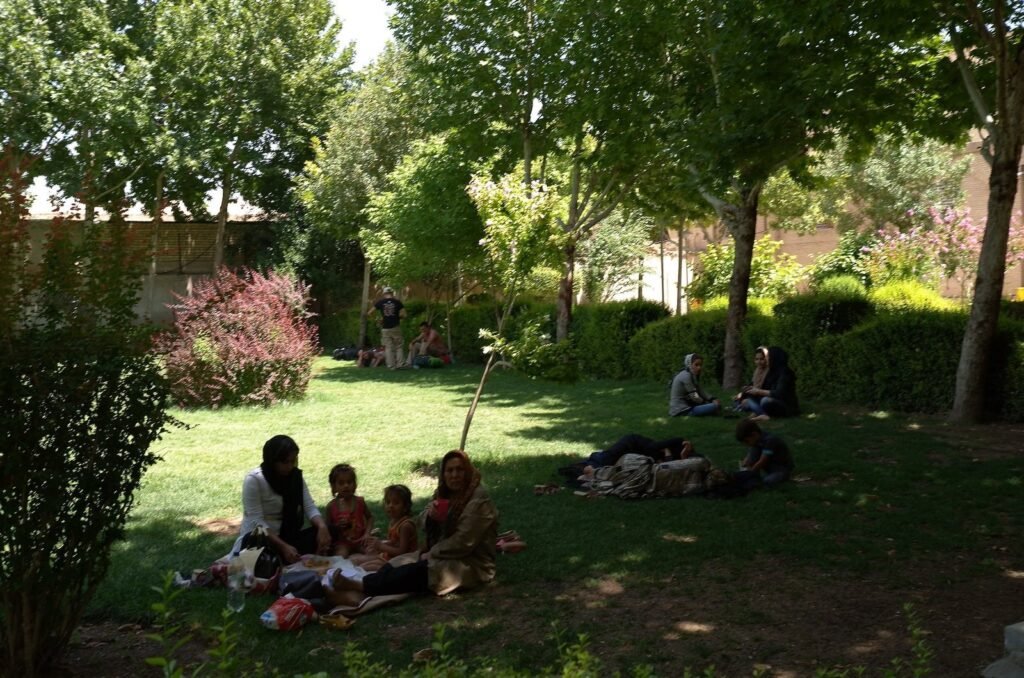 Families who rest on the grass in the garden of Chehel Sotoun Palace