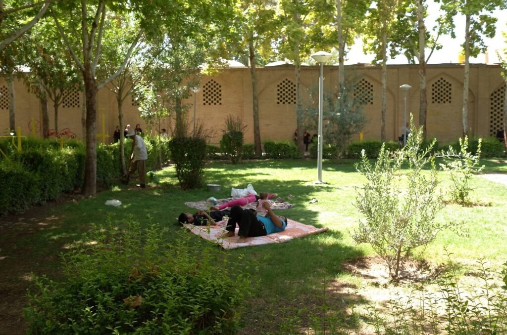 People who rest on a rug in the garden of Chehel Sotoun