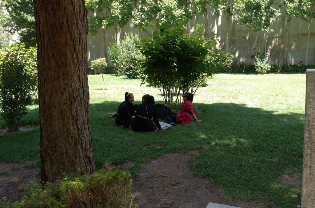 Women who sit under trees in the garden of Chehel Sotoun Palace