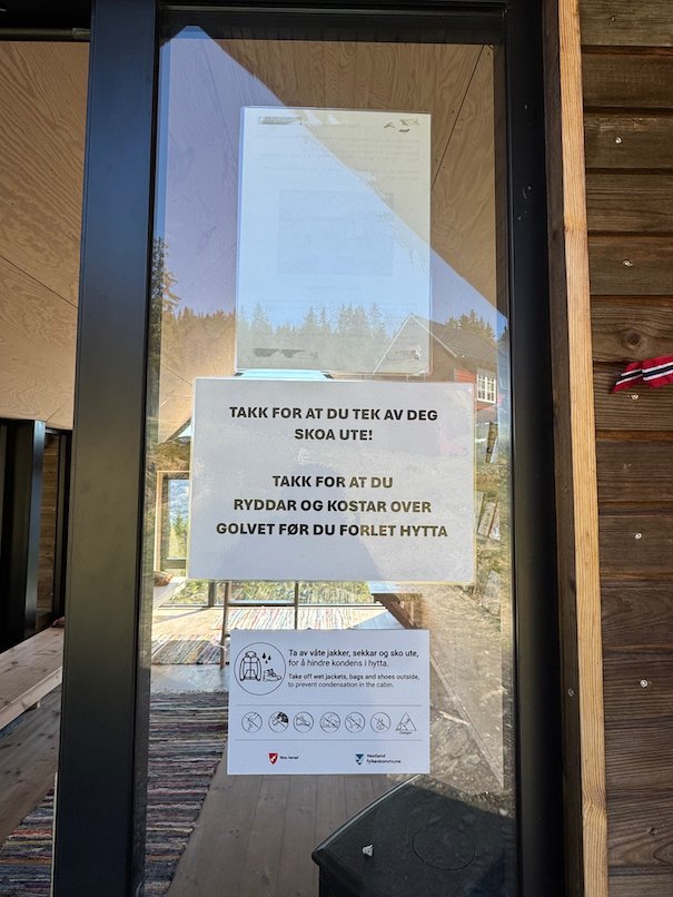 Notices on the glass door of Dagsturhytta that ask visitors to take off their shoes and sweep the floor