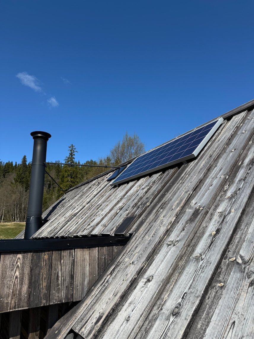 Wooden roof of Dagsturhytta with a solar panel and a black chimney