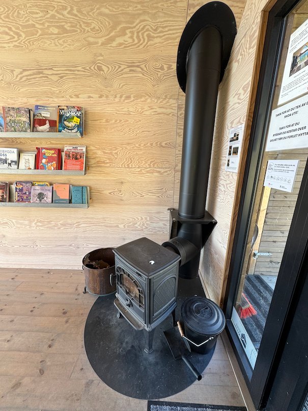 Black wood stove and shelves with books inside Dagsturhytta
