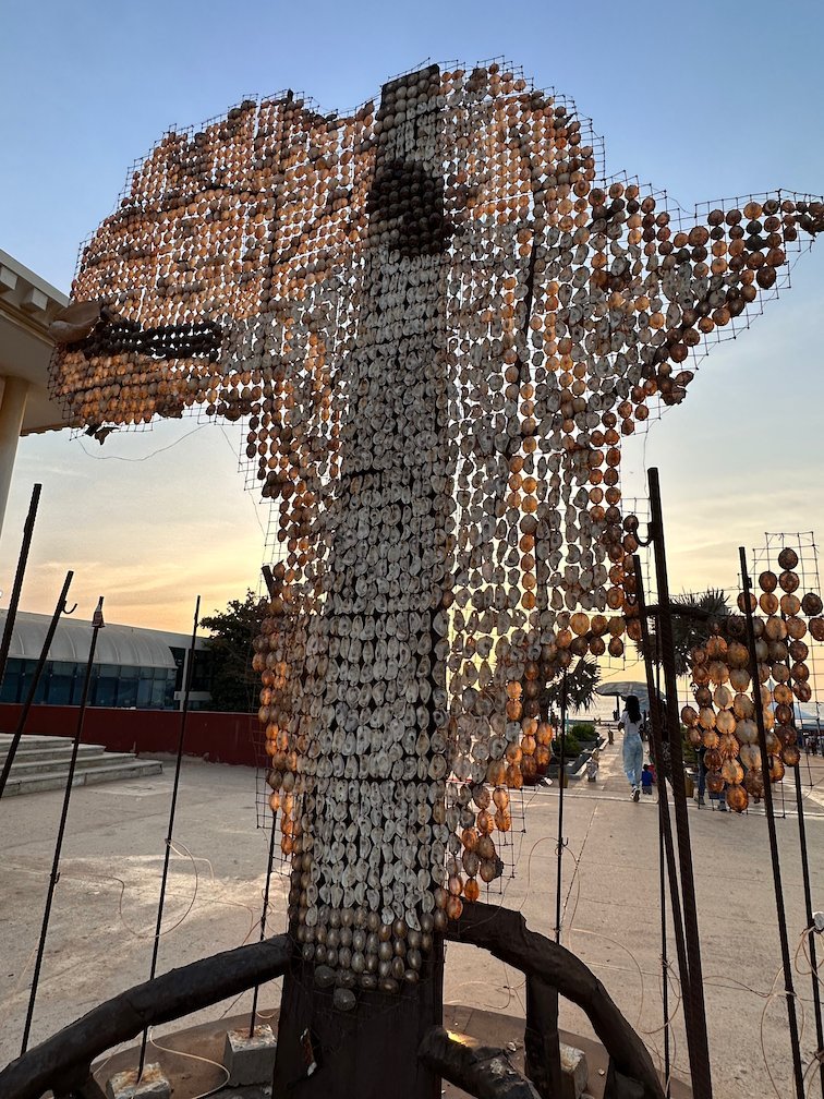A metal sculpture made of small discs is shaped like the map of Africa.