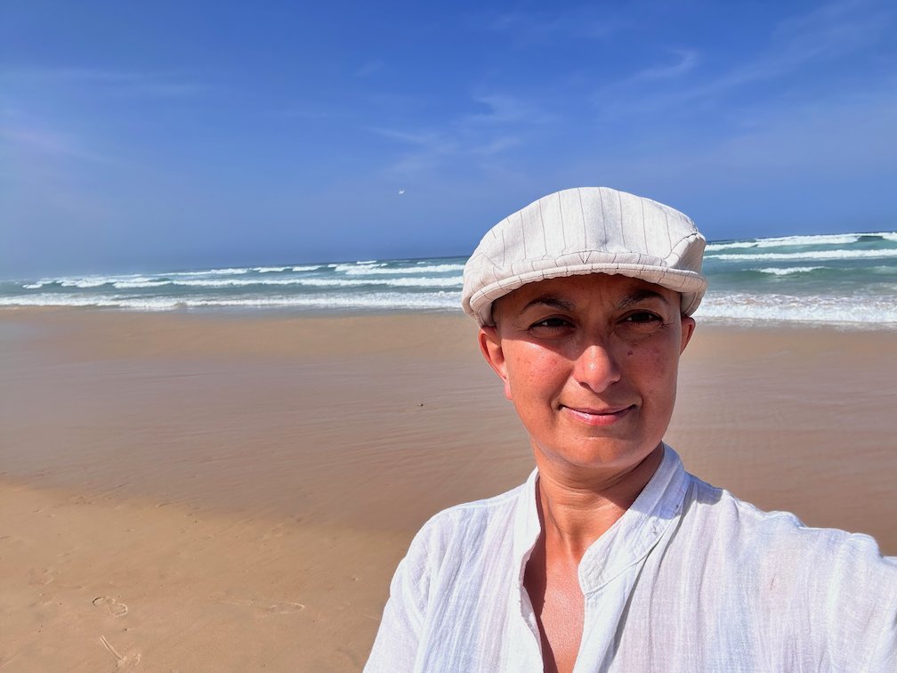 Zayera Khan in a white cap takes a selfie on a beach in Dakar.