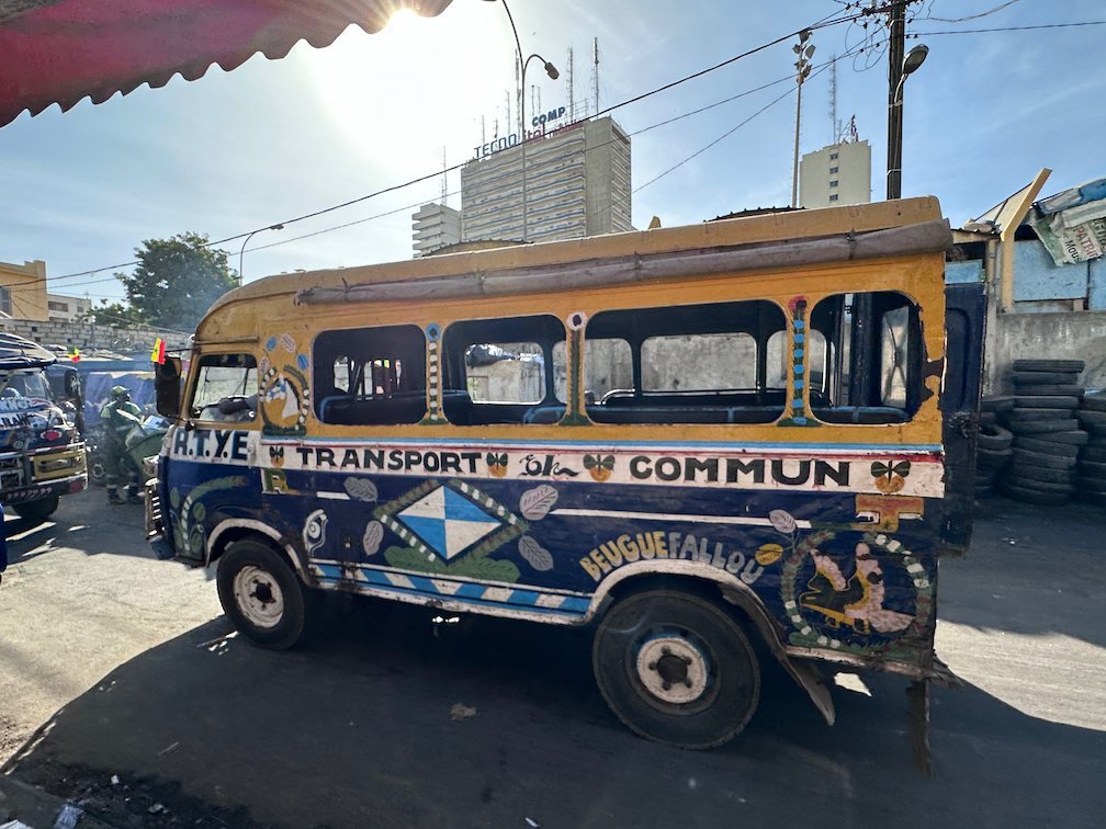 A painted blue and yellow minibus stands on a street in Dakar.