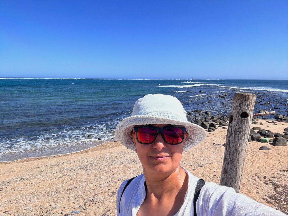 Zayera Khan in a white hat takes a selfie on the rocky coast of Dakar.