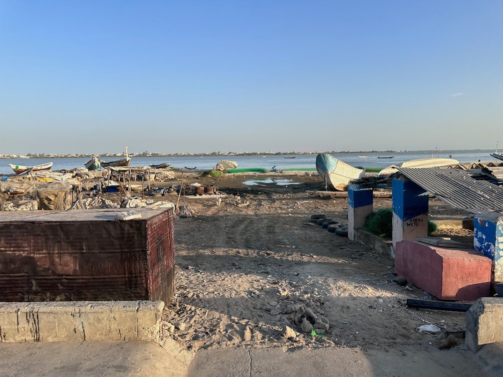 Fishing boats lie on the shore behind a wall in Dakar.