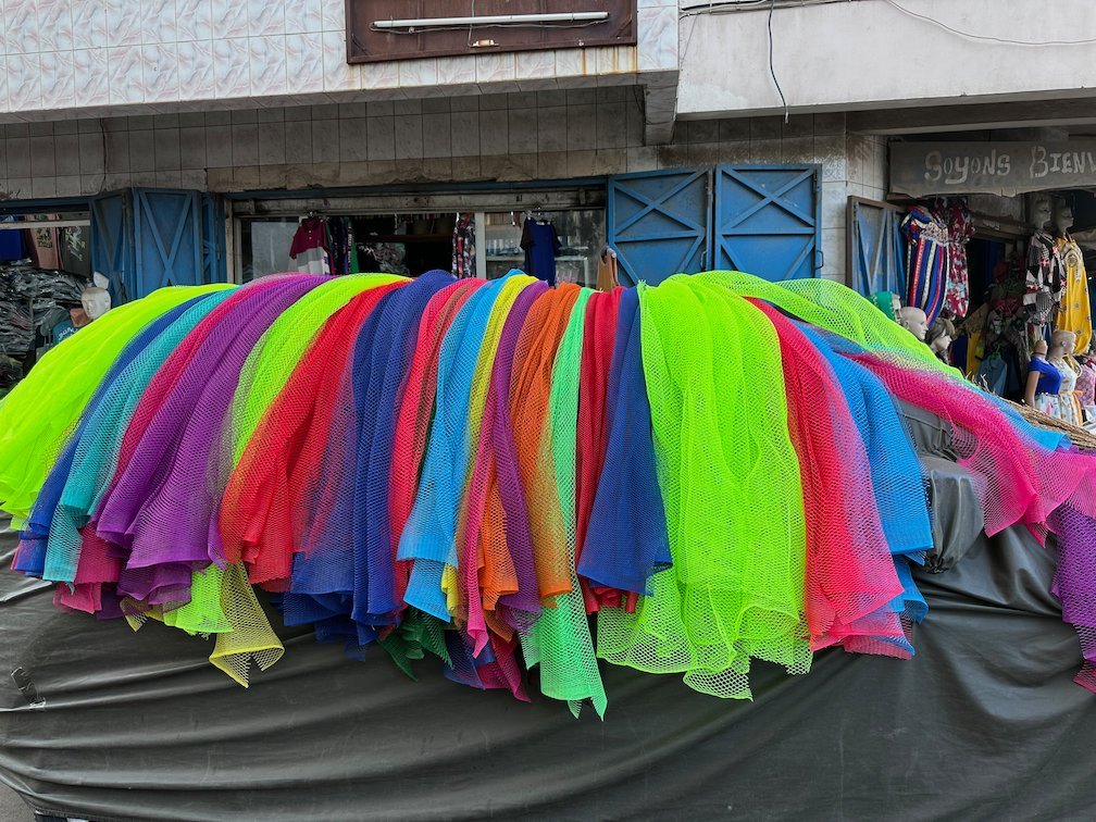Bright tulle skirts in many colors hang over a market stall in Dakar.