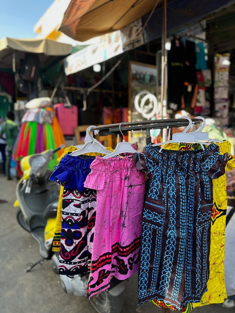 Colorful printed dresses hang on a rack at a market in Dakar.