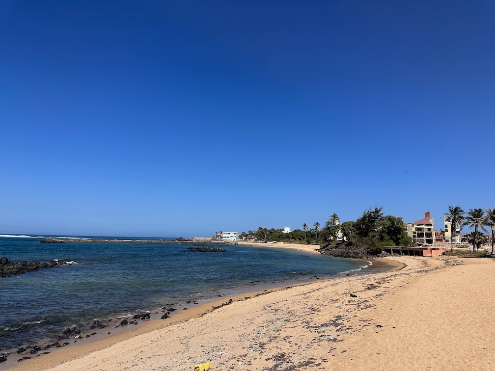 A small sandy bay with rocks and calm blue water on the coast of Dakar.