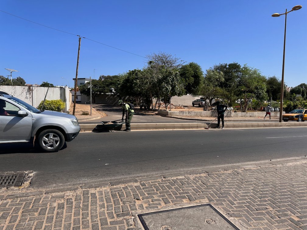 A car drives on a street with trees in Dakar.
