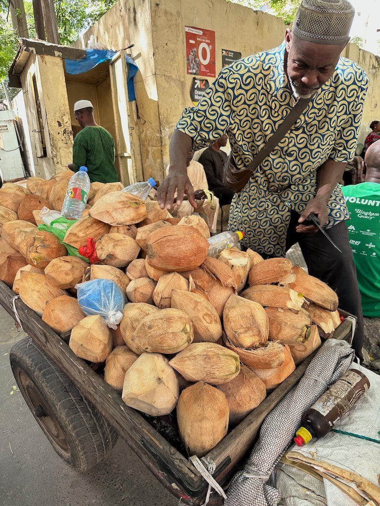 A street vendor sells brown fruits from a wooden cart in Dakar.