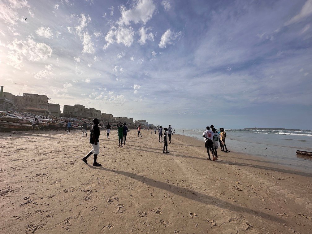 Young men play football on Yoff beach in the evening.