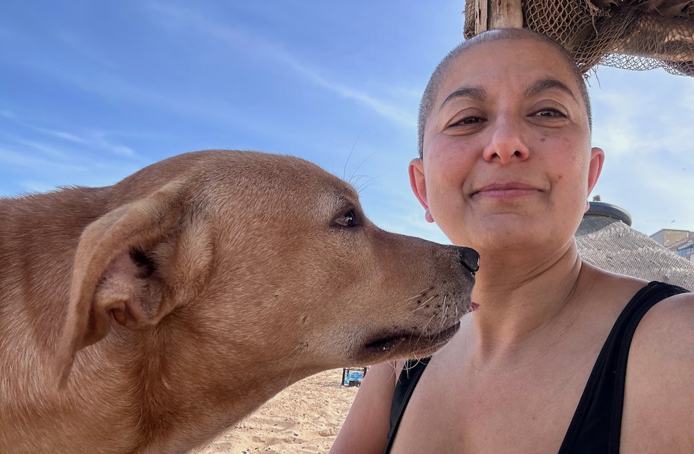 A street dog licks the face of Zayera Khan in a selfie on Yoff beach.
