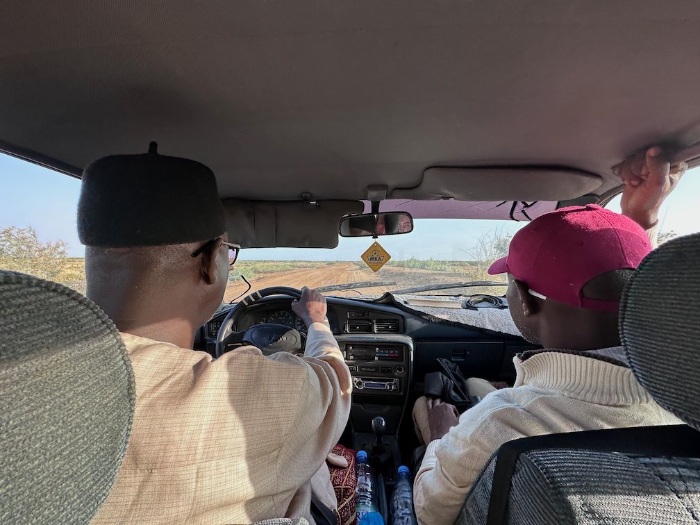 A driver and a guide sit in the front of a yellow taxi near Djoudj.