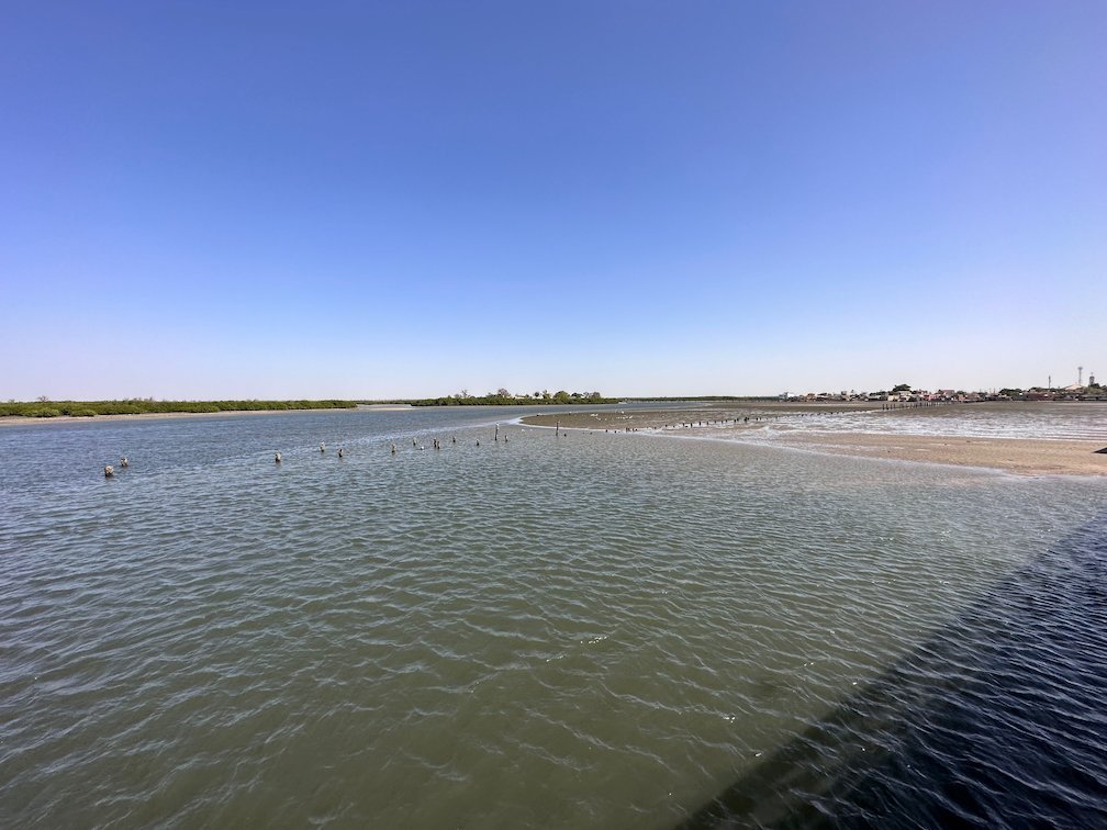 The calm lagoon water reaches to green mangroves near Fadiouth.