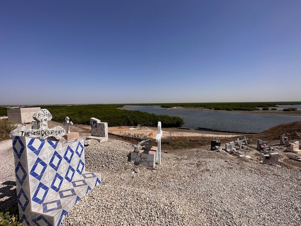 A grave with blue and white tiles stands near the lagoon in Fadiouth.