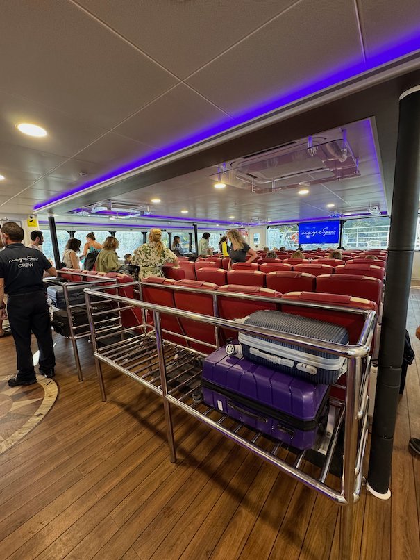 Luggage rack with suitcases and passengers inside the fast ferry to Hydra