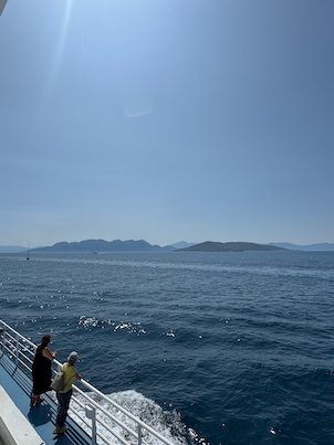 Passengers at the rail of the ferry deck, with islands in the Saronic Gulf