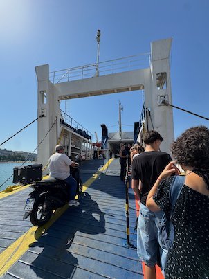 Passengers and a scooter rider on the open ferry ramp at Piraeus