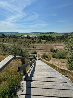 Wooden boardwalk and steps down the Fjärås Bräcka ice age ridge, with open land beyond