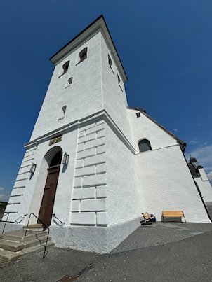 White tower of Fjärås church seen from below, with the arched entrance door