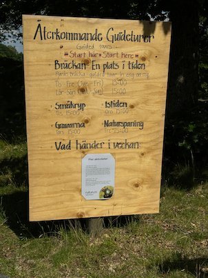 Hand-painted wooden sign in Swedish about guided tours at Fjärås Bräcka