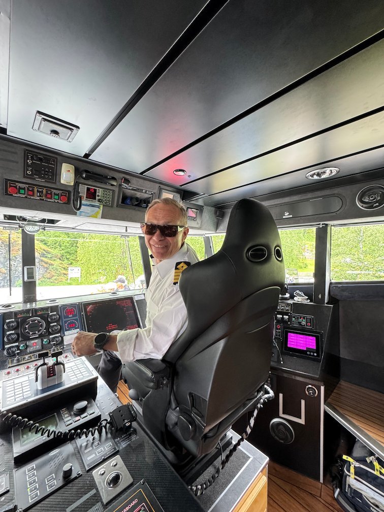 Captain at the helm on the bridge of the fjord boat