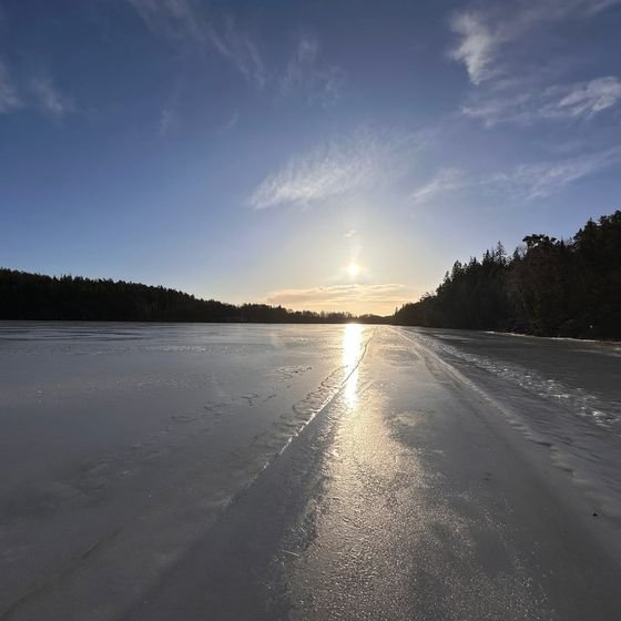 The sun sets low over a frozen lake, casting light across the ice, near Stockholm in winter, photographed by Zayera Khan