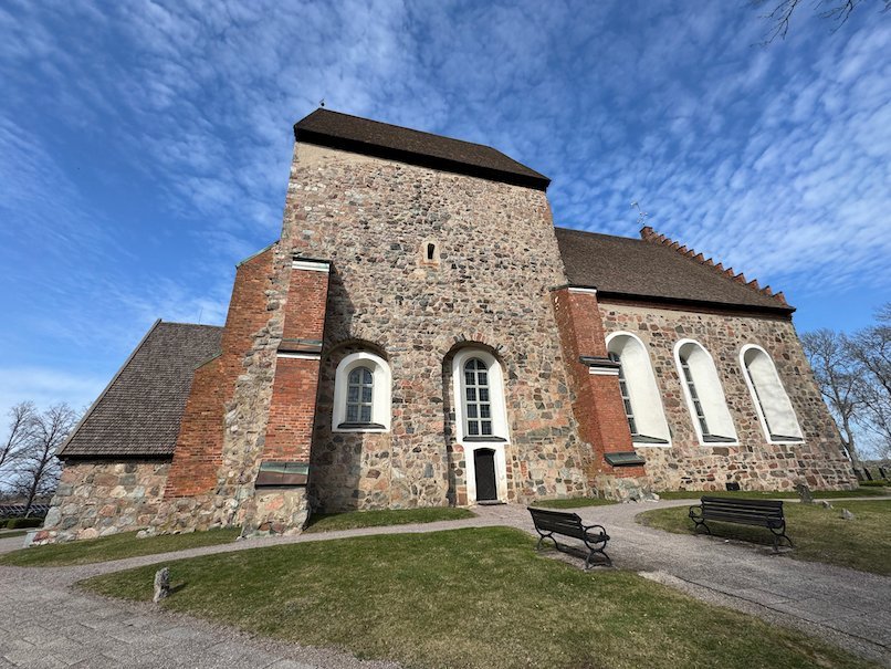 Gamla Uppsala church from the east, with grey stone walls, red brick details and arched windows