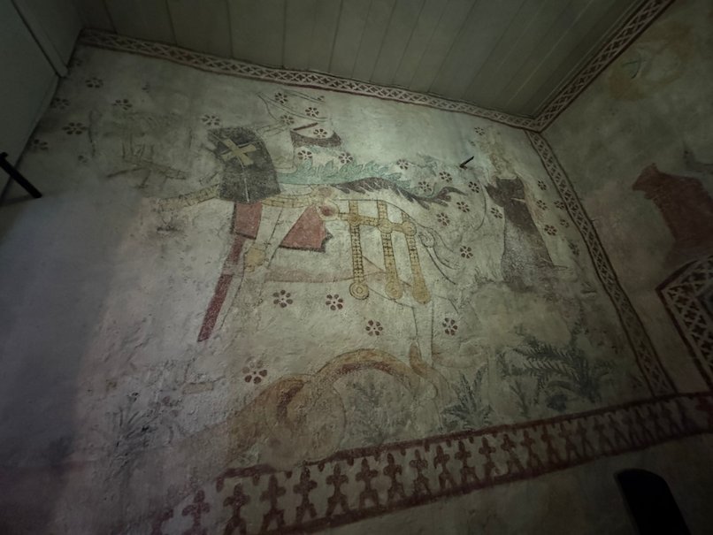 Faded medieval wall painting of a rider on a horse inside Gamla Uppsala church