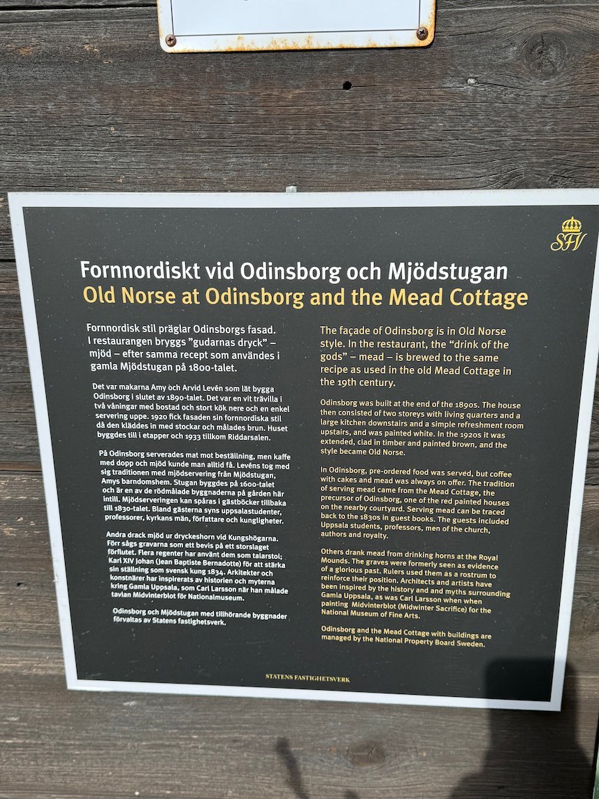 Information sign Old Norse at Odinsborg and the Mead Cottage, on a dark wooden wall